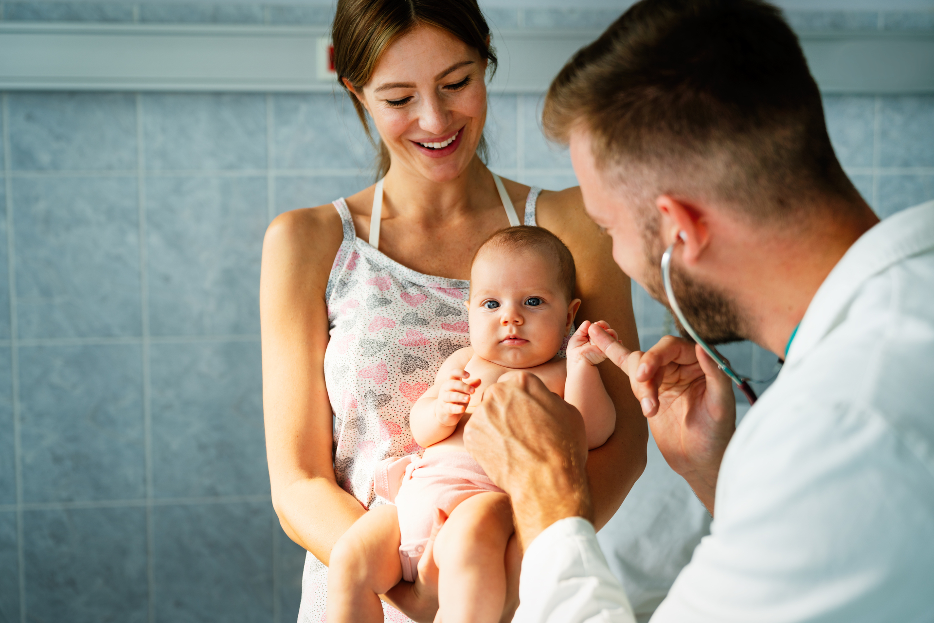 Mother holding baby for pediatrician doctor to examine